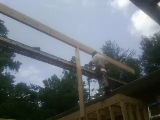 Carpenter setting a ridge beam over a new addition frame — Ice Dam Removal by Roofing Brothers in Kathleen
