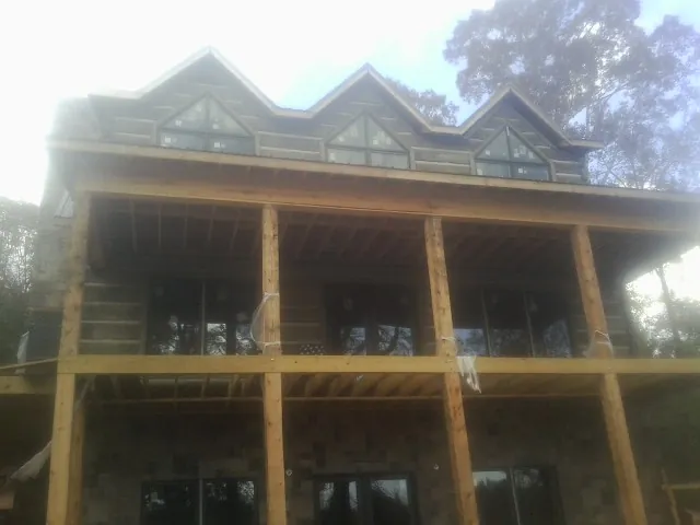 Dormers and porch framing on a large log home under construction — Roof Coating work by our crew in Kathleen