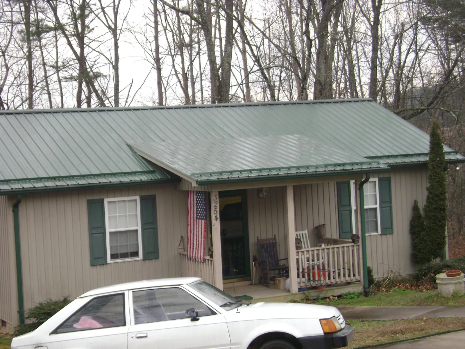Green metal roof and front porch on a tan sided cottage in Kathleen